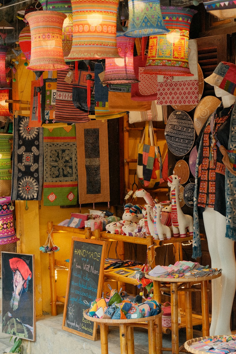 Handmade textile goods displayed in a shop window with signage.